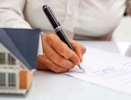 lakáshitel lakásbiztosítás nélkül - férfi aláírja az adásvételi szerződést