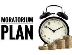 Ébresztőóra és pénzérmék a "MORATORIUM PLAN" felirat mellett.