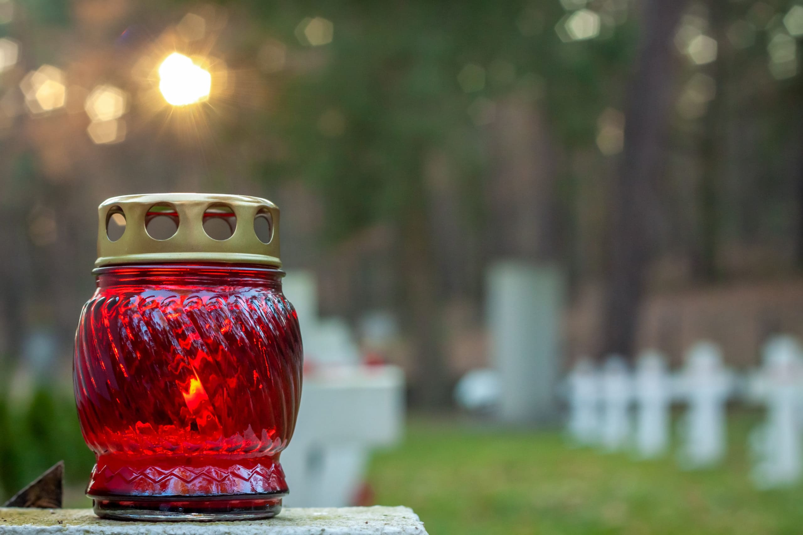Égő piros temetői üvegmécses.