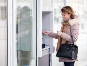 Egy hölgy ATM-ből vesz fel készpénzt.