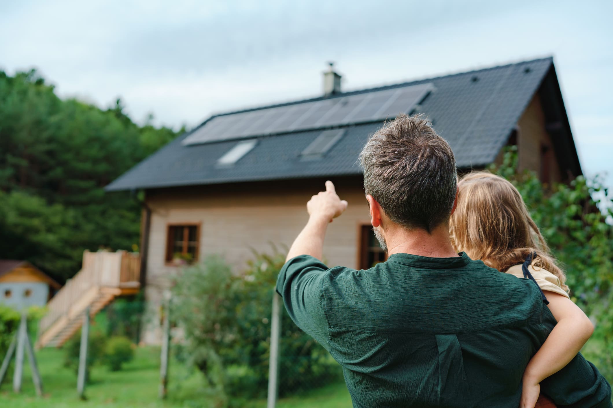 Egy apa és lánya nézik a zöld energiatakarékos házat.