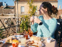nő asztalnál ül és reggelizik Szicíliában, külföldi nyaraláson, euró váltása után