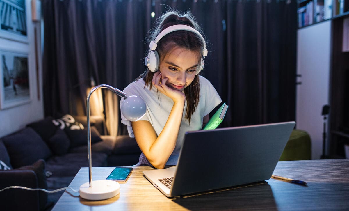 egyetemista lány laptop előtt asztalnál tanul a saját lakásában