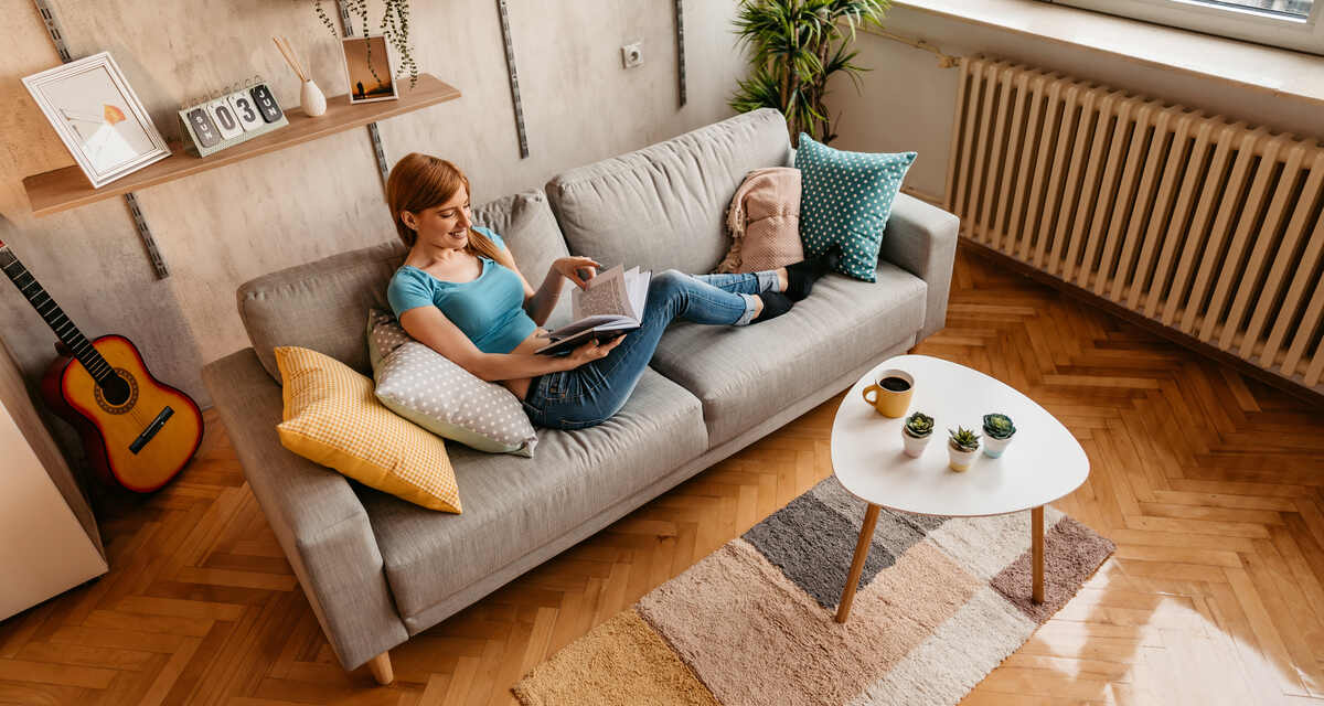 nő a nappali kanapéján olvas a lakáshitelből vett lakásában, BIRS, infláció
