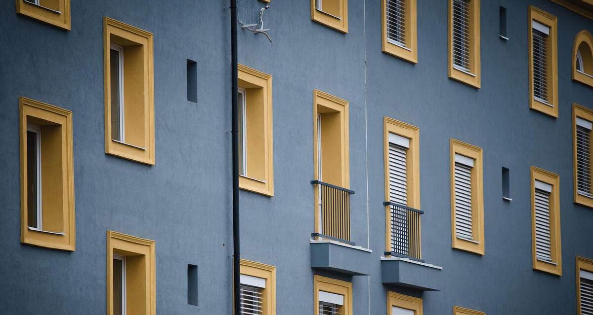 lakóparki bérház ablakai, erkélyei, kék és sárga, mnb kamatdöntés