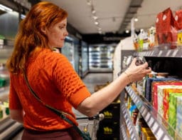 narancs pulóveres vörös hölgy a szupermarketben, hipermarketben, boltban vásárol élelmiszert, infláció idején