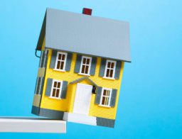 miniatűr házikó a szakadék szélén, egy lakásbiztosítás védi
