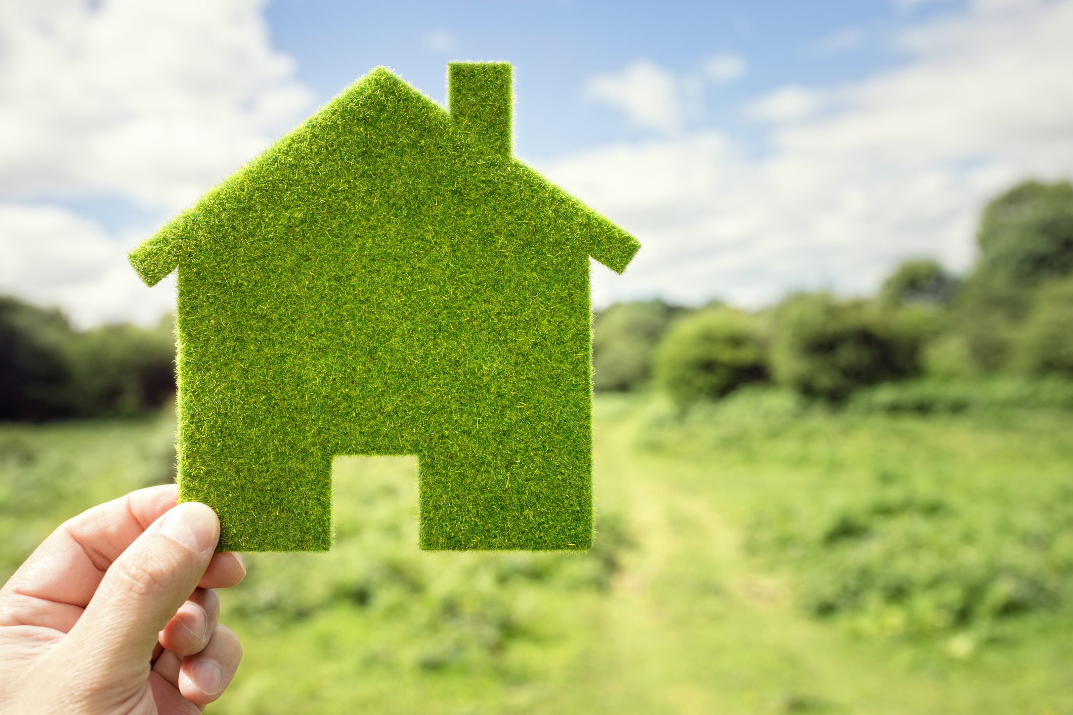 Zöld energiahatékony ház szimbólum, zöld táj háttér előtt
