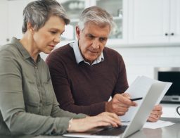 Egy nyugdíjas pár néz valamit papíron, laptopon.