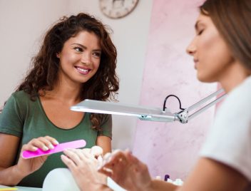 szépségszalonban két nő manikűr közben, a műkörmös hölgy munkáshitelt is igényelhet, önerőként is használhatja