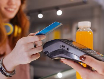 fiatal lány pos-terminálnál fizet kártyával, bankkártya lejárati dátum a kártya előlapján