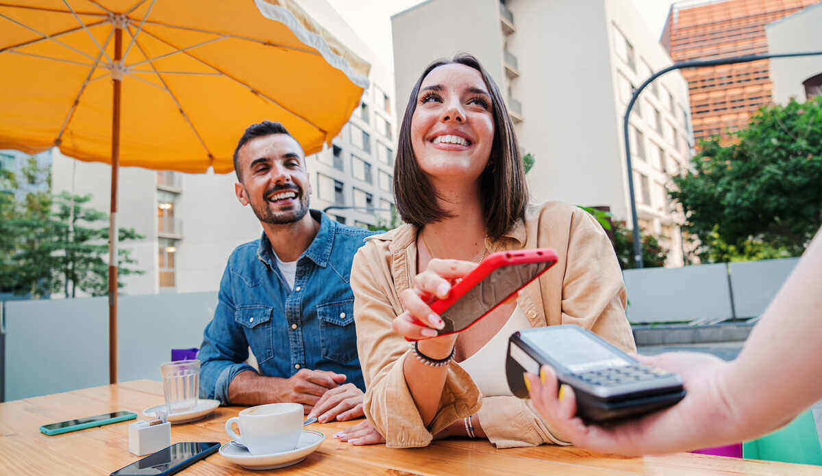 fiatal pár fizet a kávéért telefonnal, revolutról átutalás