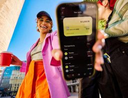 gen z nő a mobilbankok funkcióit mutatja az utcán, kávéval a kezében