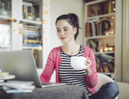 Ügyek intézése otthonról: egy fiatal nő az internet előtt a laptopján intézi banki ügyeit.