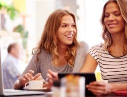 Női ikerpár kávézóban notebookkal