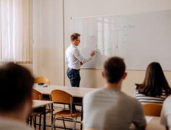 Tanár áll a fehér filces táblánál