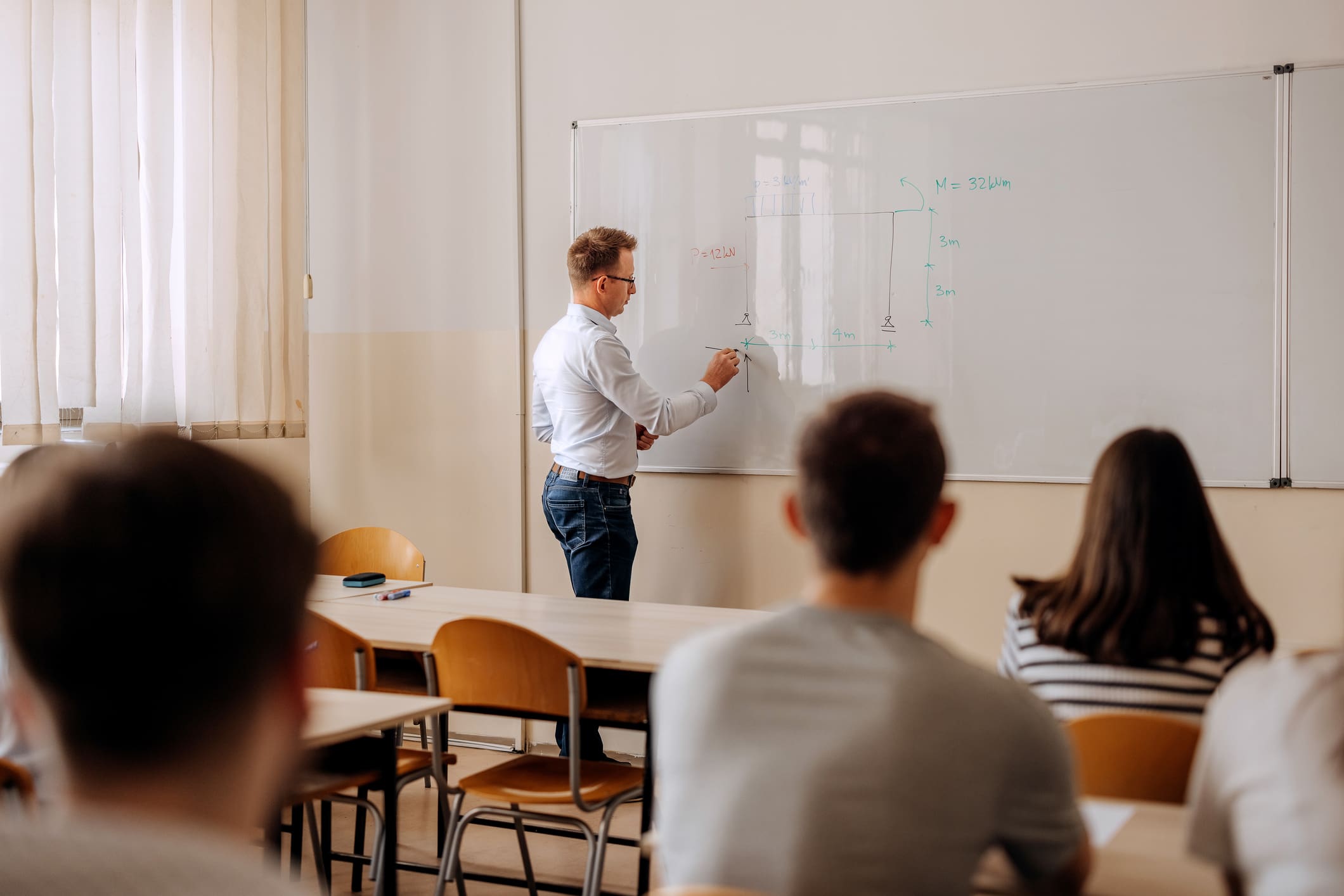 Tanár áll a fehér filces táblánál