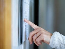 Egy nő a mutatóujjával egy napra mutat egy falinaptáron