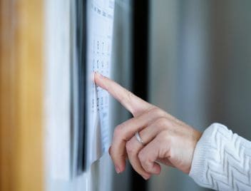 Egy nő a mutatóujjával egy napra mutat egy falinaptáron