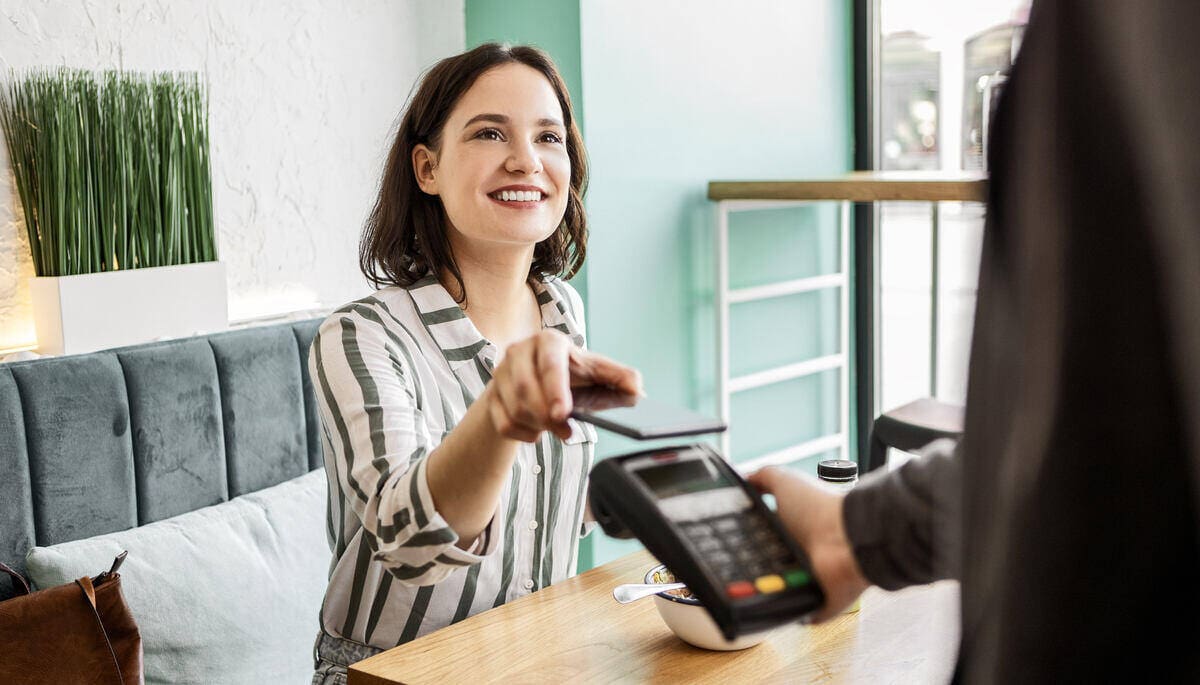 nő telefonnal fizet a legolcsóbb bankszámláról