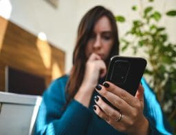 Gyanús üzenet észlelése a mobiltelefonon egy fiatal nő által.