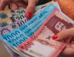 Magyar forint bankjegyek egy piros körömlakkos nő kezében.