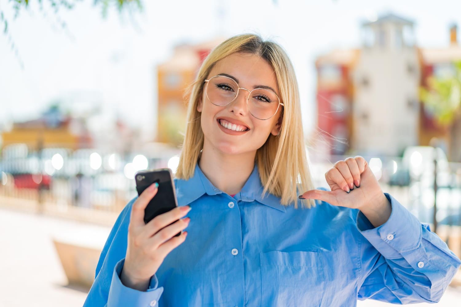 Fiatal, szemüveges lány örül a mobiltelefonjára kapott hírnek.