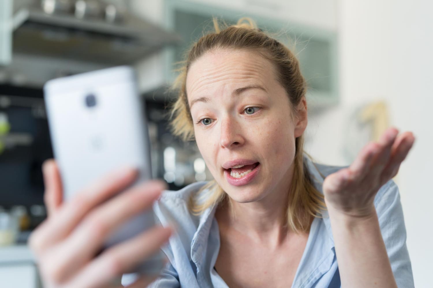 Egy fial nő nézi a mobiltelefonját és értetlen arcot vág.