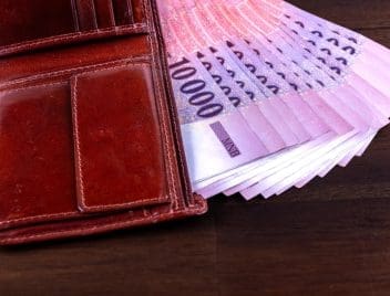 Magyar 10 ezer forintos köteg lóg ki egy barna bőr nyitott pénztárcából.