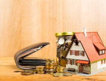 Házikó ikon, aprópénzzel teli befőttesüveg és egy bankjegyekkel teli pénztárca látható a képen - finanszírozási megoldások szemléltetése.